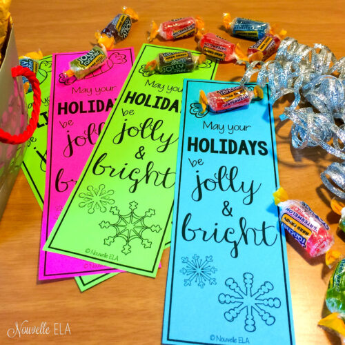 A photo of three bookmarks, green, pink, and blue, that say "May your holidays be jolly and bright" and they are surrouded by ribbon and jolly rancher candies
