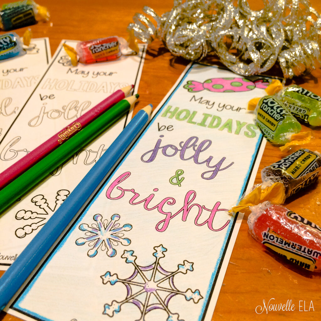 A photo of bookmarks, colored pencils, silver ribbon, and Jolly Rancher candies on a wooden tabletop. The bookmarks say "May your holidays by jolly and bright"